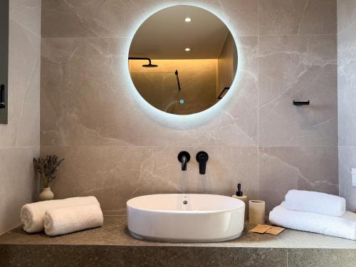 a bathroom with a tub and a round mirror at Elia Stay in Kalives Poligirou
