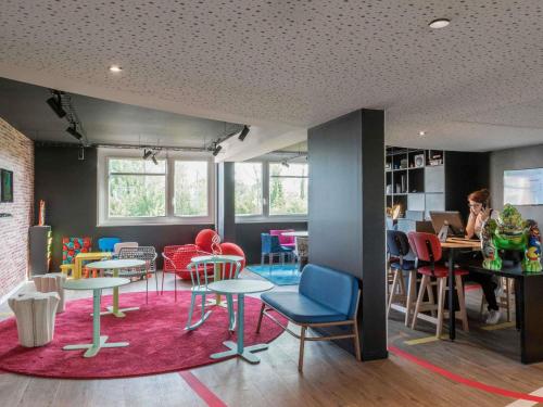 a room with tables and chairs and people sitting at desks at ibis Styles Lyon Bron Eurexpo in Bron