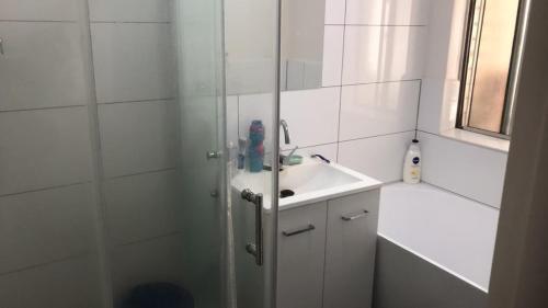 a white bathroom with a shower and a sink at R1 Bright Spacious Room near Perth Airport in Perth