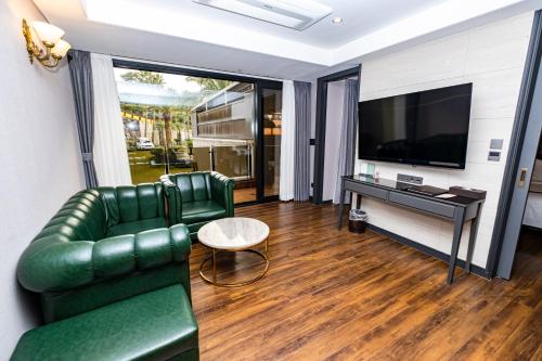 a living room with a green leather couch and a television at Dyne Oceano Hotel in Jeju