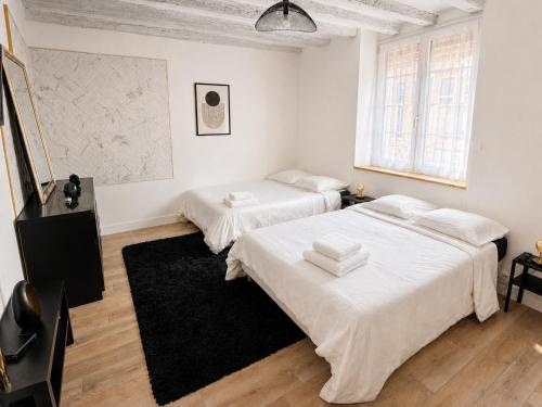two beds in a white room with a black rug at Grand appart 6 pers Cœur de Nemours in Nemours