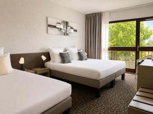 a hotel room with two beds and a window at Hôtel-Restaurant La Belle Poule - in Rochefort
