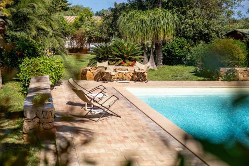 a swimming pool with two chairs and a table and a table and a pool at Agriturismo Duca di Castelmonte in Trapani