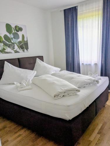 a large bed with white sheets and pillows on it at Nassfeldpass Pistenblick in Sonnenalpe Nassfeld