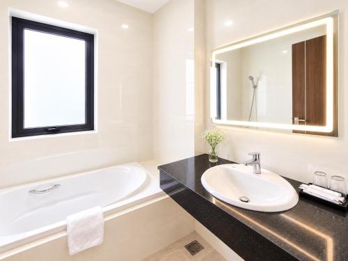 a bathroom with a sink and a tub and a mirror at Saffron Boutique Hotel in Da Lat