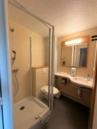 a bathroom with a shower and a toilet and a sink at Hôtel Inn Design Montluçon in Montluçon