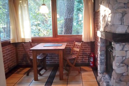 a table and chairs in a room with a stone fireplace at Cabañas El Ocio in Mar de las Pampas
