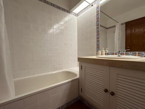a bathroom with a tub and a sink and a bath tubermottermott at Solar Pinheiros RC in Vilamoura