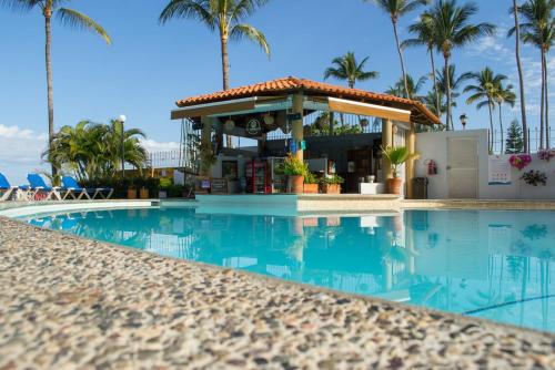 a swimming pool with a kiosk next to a resort at Cabañas del Capitan in Rincon de Guayabitos