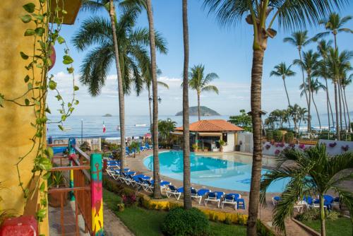 a view of the pool at a resort with palm trees at Cabañas del Capitan in Rincon de Guayabitos