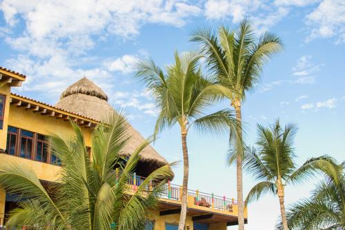 a resort with palm trees in front of a building at Cabañas del Capitan in Rincon de Guayabitos