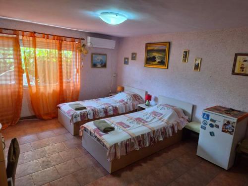 a bedroom with two beds and a refrigerator at Стаи за гости Дворъ in Varna City