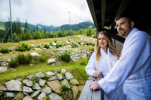 a man and a woman standing on a balcony with a glass of wine at Chalets Jasná Collection Centrum in Belá
