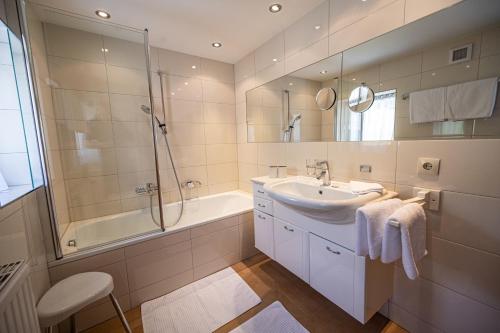 a bathroom with a sink and a shower and a tub at Pension Hartenfels in Lech am Arlberg
