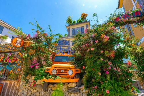 an orange truck parked in front of a building with flowers at Sweet August · Boutique Hotel (Dali Erhai) in Dali
