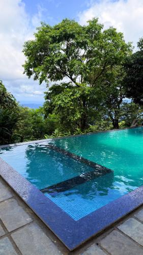 a pool of blue water with trees in the background at GAIRAH RESORT in Mundakāyam