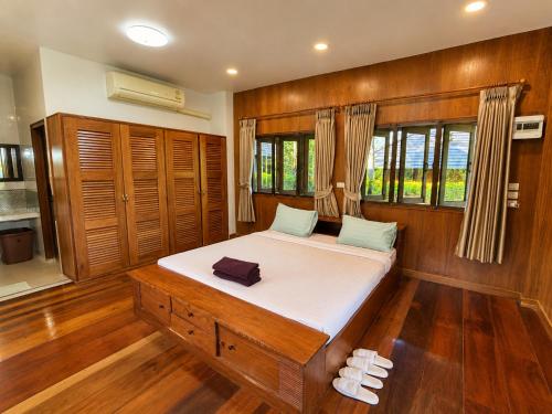 a bed in a room with wooden floors and windows at Aruna Mountain Lodge in Ban Huai Rin