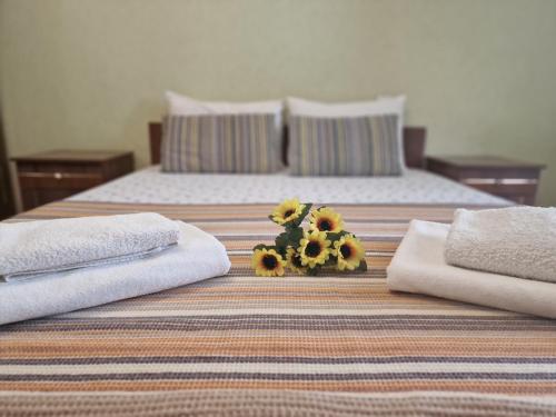 a bedroom with two beds with towels and a bouquet of sunflowers at Three Rooms Comfort in Chişinău