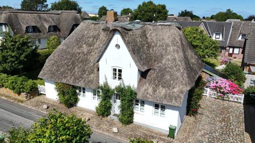 an old white house with a thatched roof at Haus Oevenum in Oevenum