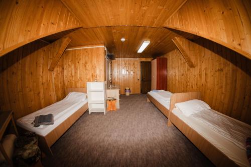 two beds in a room with wooden walls at FELIX hostel in Dumbrăveni