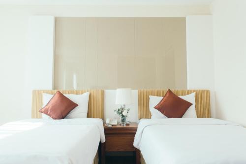 two beds sitting next to each other in a bedroom at Thomson Residence Hotel in Bangkok