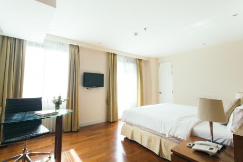 a hotel room with a bed and a television at Thomson Residence Hotel in Bangkok