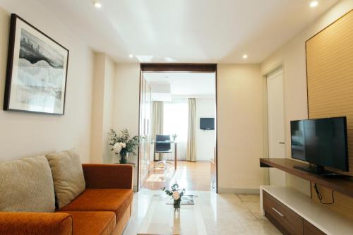 a living room with a couch and a flat screen tv at Thomson Residence Hotel in Bangkok