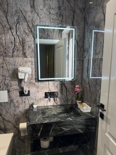 ein Badezimmer mit Marmorwaschbecken und Spiegel in der Unterkunft Hotel Muja in Rinas