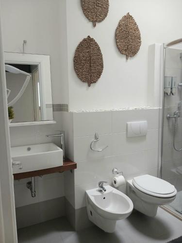 a white bathroom with a toilet and a sink at B&B Colori del Salento in Presicce