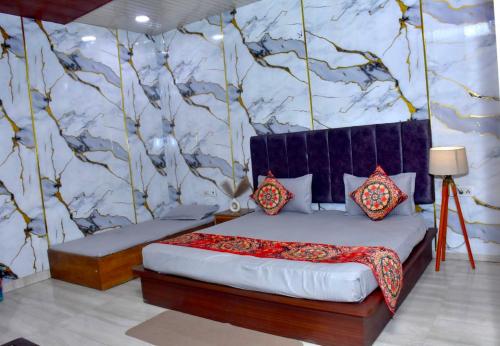 a bedroom with a bed and a wall with trees at Queen Palace in Mathura
