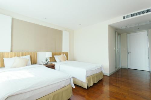 two beds in a hotel room with wooden floors at Thomson Residence Hotel in Bangkok