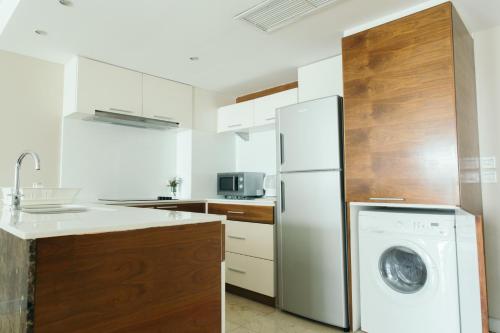 a kitchen with a white refrigerator and a washing machine at Thomson Residence Hotel in Bangkok