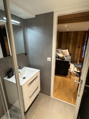 a bathroom with a sink and a room with a couch at Studio alpin au centre de la station in Saas-Fee
