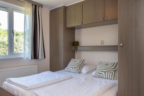 a bedroom with two beds and a window at Chalet dichtbij strand Vrouwenpolder in Serooskerke