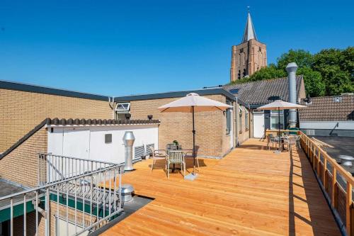 a wooden deck with umbrellas on top of a building at Boven restaurant de Babbelaar 1 in Oostkapelle