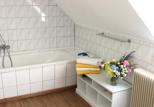 a white bathroom with a tub and a vase of flowers at Schenkenhof Proitze in Schnega