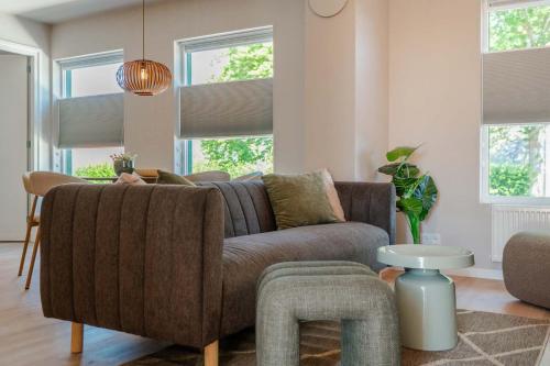a living room with a brown couch and windows at Boven restaurant de Babbelaar 2 in Oostkapelle