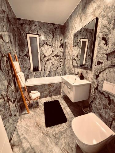 a bathroom with a rock wall with a toilet and sink at Adinna Residence in Giroc