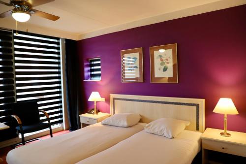a bedroom with two beds and a purple wall at City Hotel Restaurant Stadskanaal in Stadskanaal
