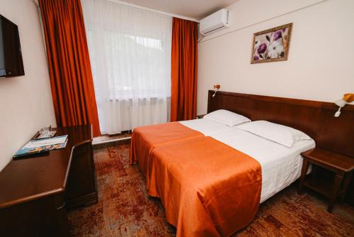 a bedroom with a large bed with an orange blanket at Hotel Ciucas in Băile Tuşnad
