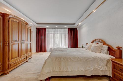 a bedroom with a large bed and red curtains at Cozy Apartment Floreasca Park in Bucharest