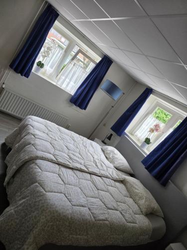 a bedroom with a large bed with blue curtains at Herberg de Griffioen in Wolphaartsdijk