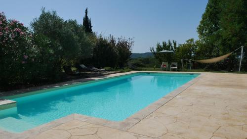 a swimming pool with blue water in a yard at A l'orée du bois - Chambres d'hôtes in Hostun