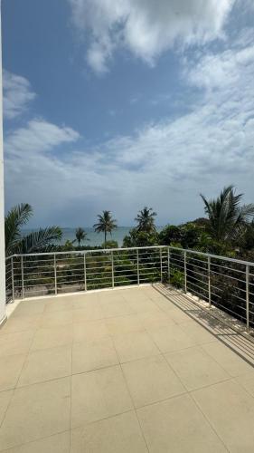 a large patio with a fence and palm trees at ZanziBlue Beach Hotel in Mfumbwi