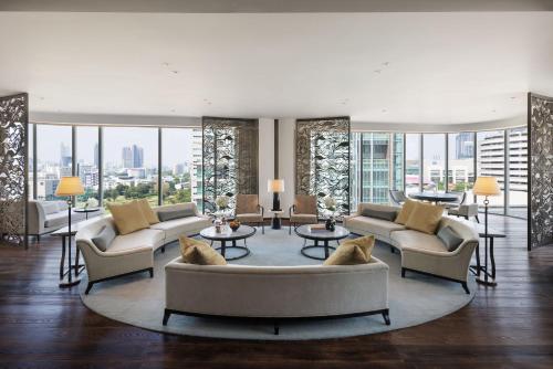 a living room with couches and tables and windows at Waldorf Astoria Bangkok in Bangkok