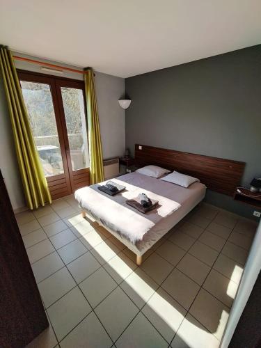 a bedroom with a bed and a large window at Auberge du Tarnon in Vébron
