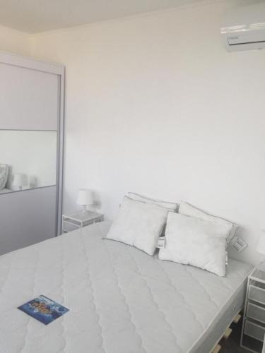 a white bed with white pillows in a white room at Dizengoff 24A in Netanya