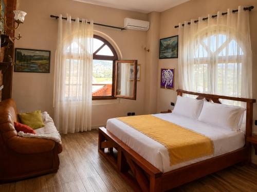 a bedroom with a bed and a chair and a window at Vila Shehi Guesthouse and Winery in Tirana