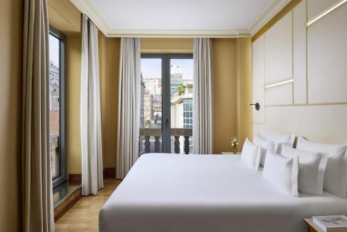 a bedroom with a large white bed and a window at NH Collection Vigo in Vigo