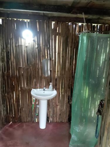 a bathroom with a white sink and a wooden wall at Casinha da Roça Java in Santa Adelaide